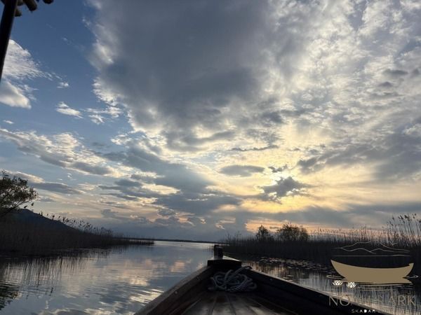 Traditional wooden boat on Lake Skadar near lily-lined channels and mountain scenery